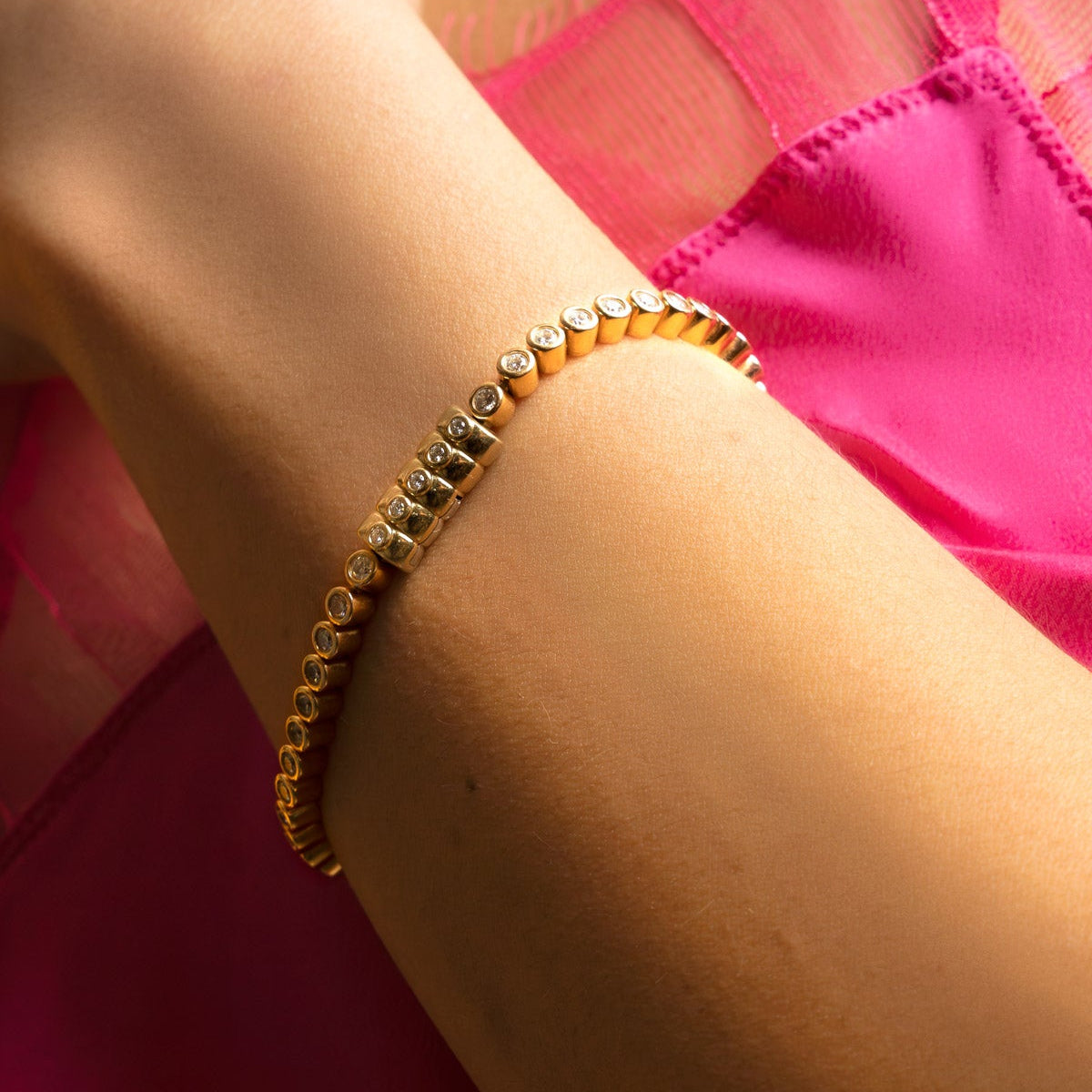 Petite Frites Bubble Tennis Bracelet with Dinner Mint Clasp in Yellow Gold on a wrist with a pink fabric background