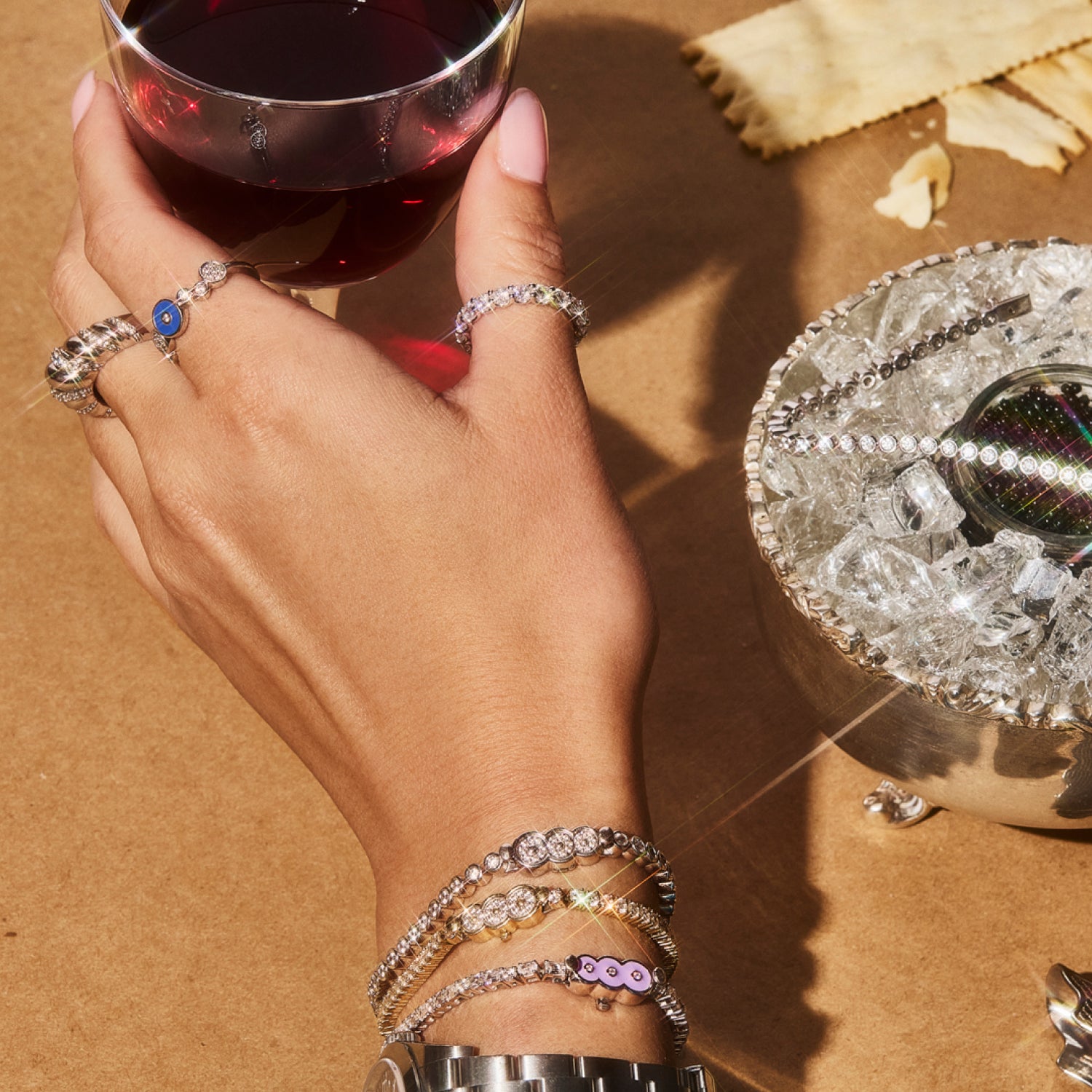 Petite Frites 18K white and yellow gold diamond tennis bracelets and rings reaching for a glass.