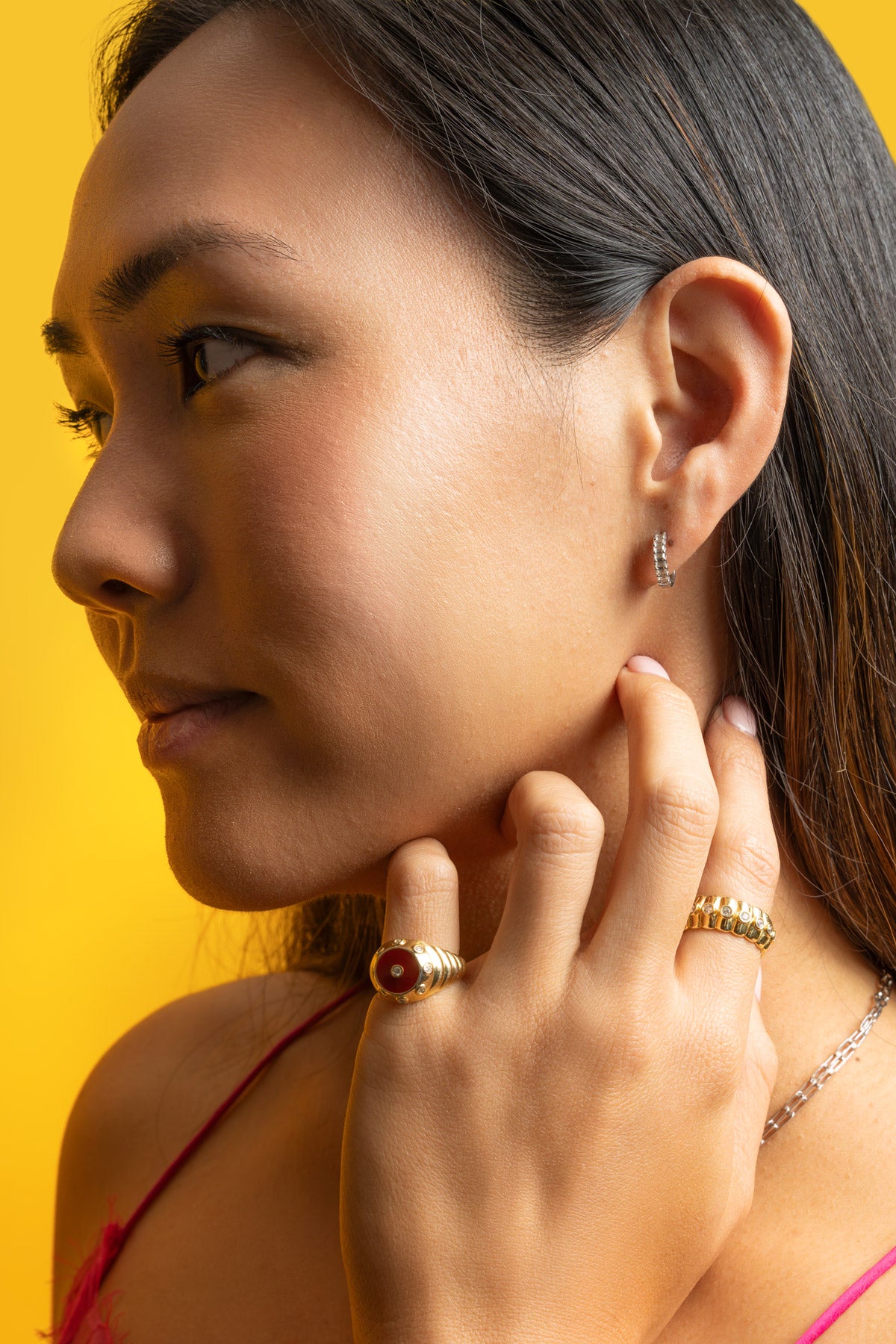Model wearing Petite Frites Candlelight earrings, Oyster Ring and Cigar Band Ring against a yellow background