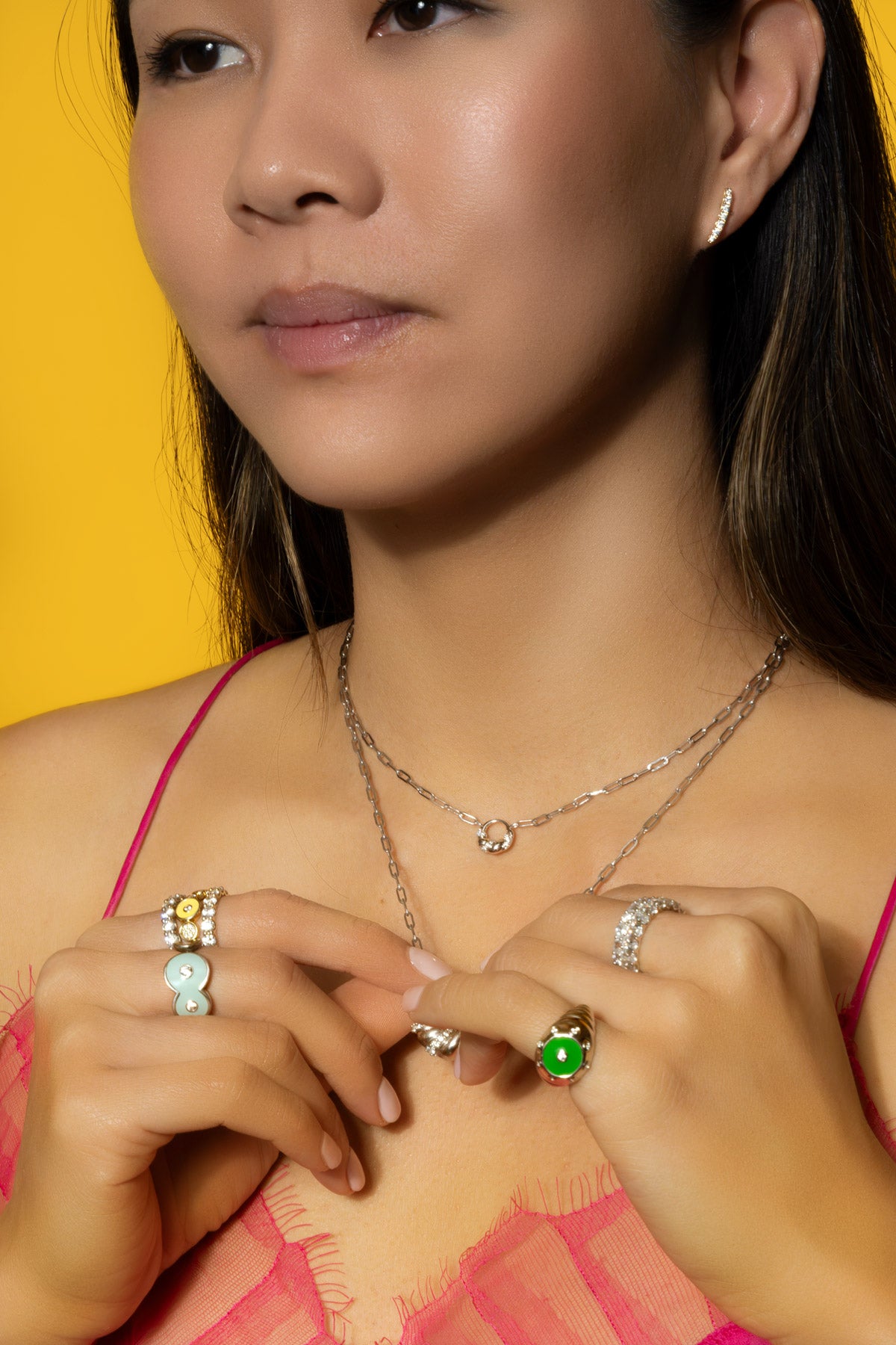 Model wearing Petite Frites Martini Ring in Sky Blue Enamel, Oyster Ring in Kelly Green Enamel, Frites Earrings, With a Twist Necklaces, and the Champagne Ring stacked with Kir Royal Rings